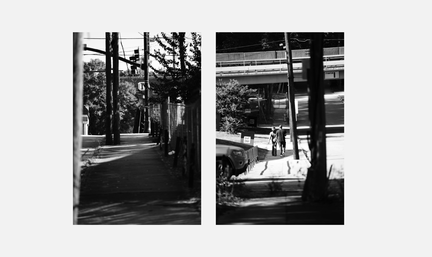 Black and white urban photography showing shadows on a city sidewalk and people walking near a bridge.