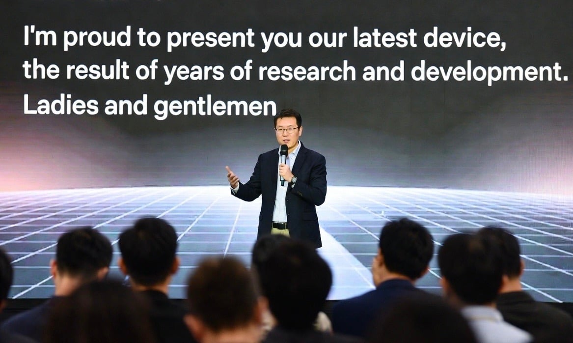 Executive presenter unveiling a new technology device during a corporate keynote product launch.