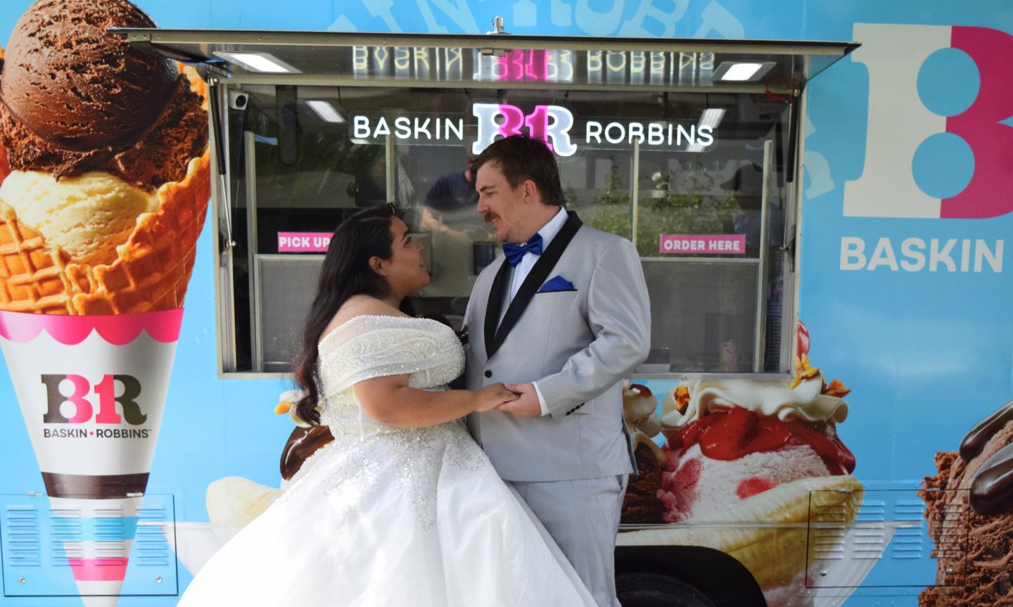Wedding couple in a dress and gray tuxedo holding hands and looking at each other while enjoying BR 
