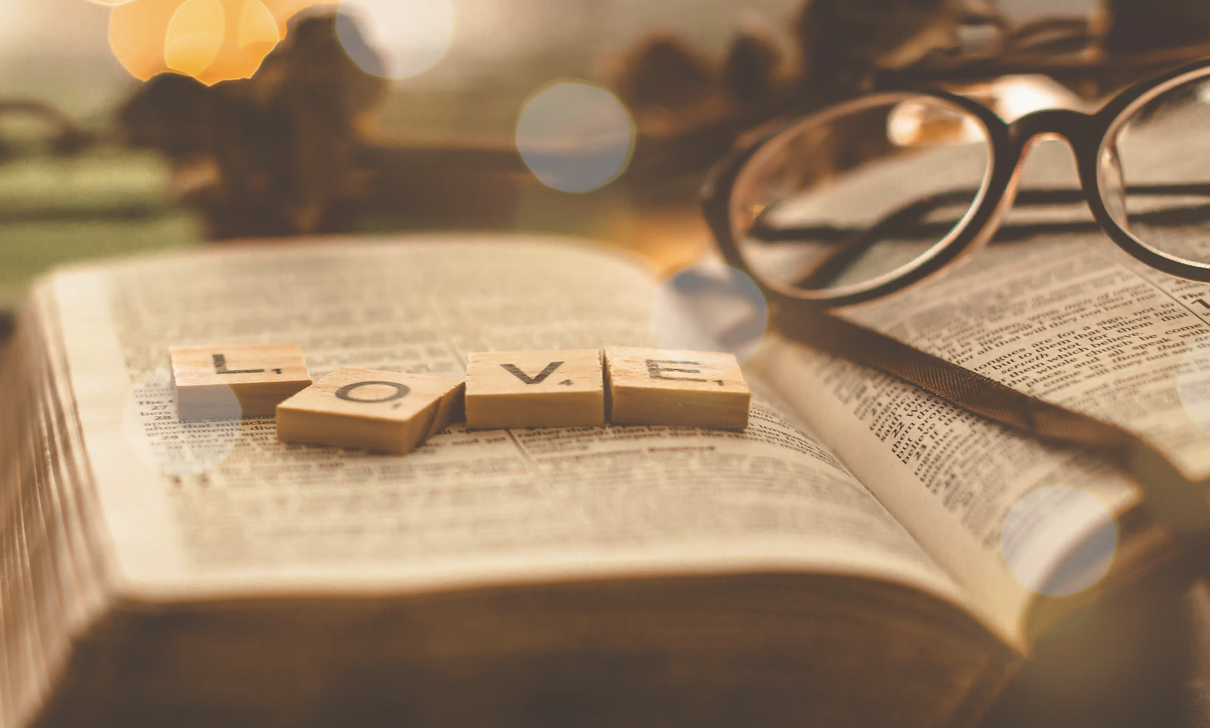 scrabble pieces spelling out the word love sitting on a book
