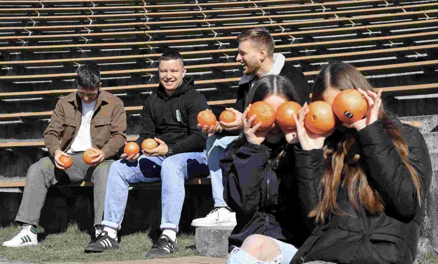 Penki jauni zmones linksmai leidzia laika, zaidzia su apelsinais