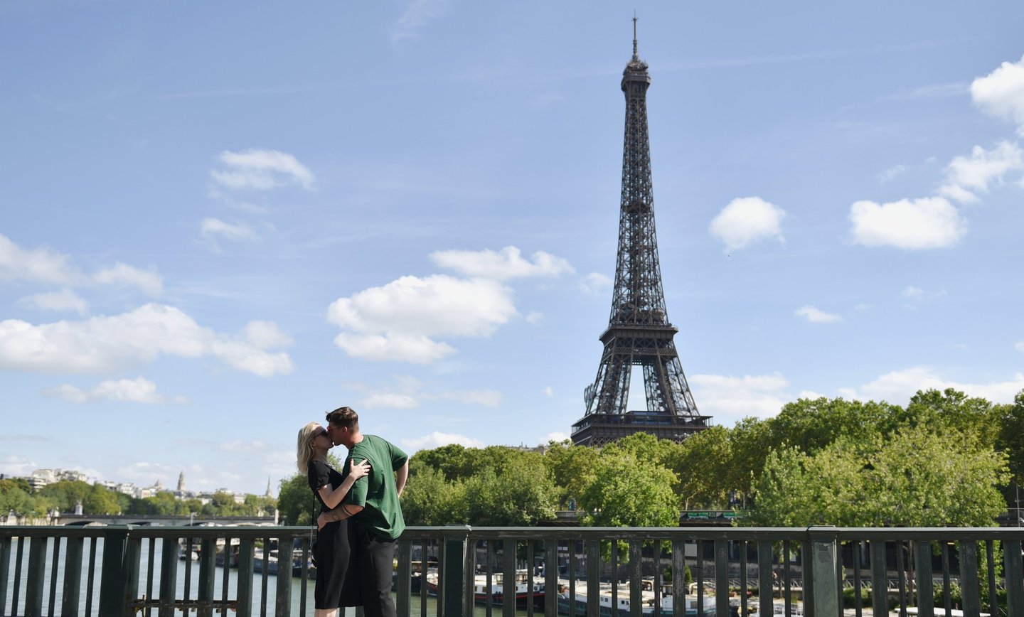 Deux amoureux s'embrassent decant la Tour Eiffel sur le pont Bir Hakeim à Paris