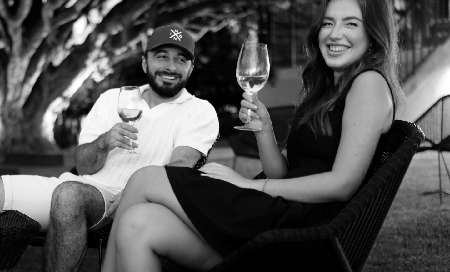 Couple enjoying wine together on outdoor terrace in Madeira, relaxing lifestyle and romantic vibe beneath leafy trees.