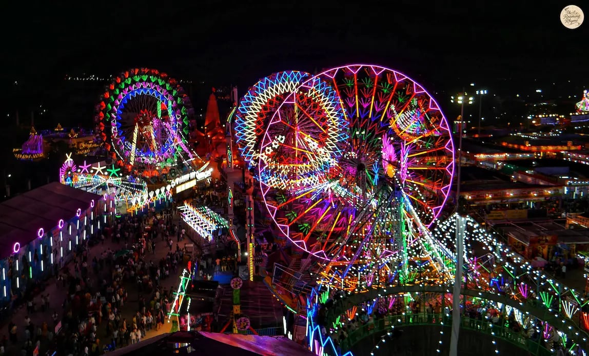 Night aerial view of Kota Dussehra Mela with glowing giant wheels, dazzling rides, and illuminated stalls.