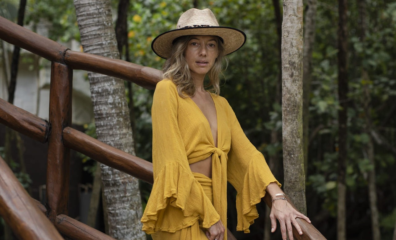 mujer usando un vestido amarillo boho chic Tulum y sombrero. con fondo en la selva
