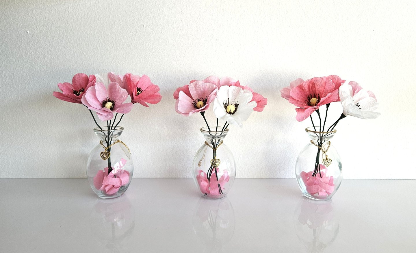 Vaasjes met roze en witte bloemen van crêpepapier