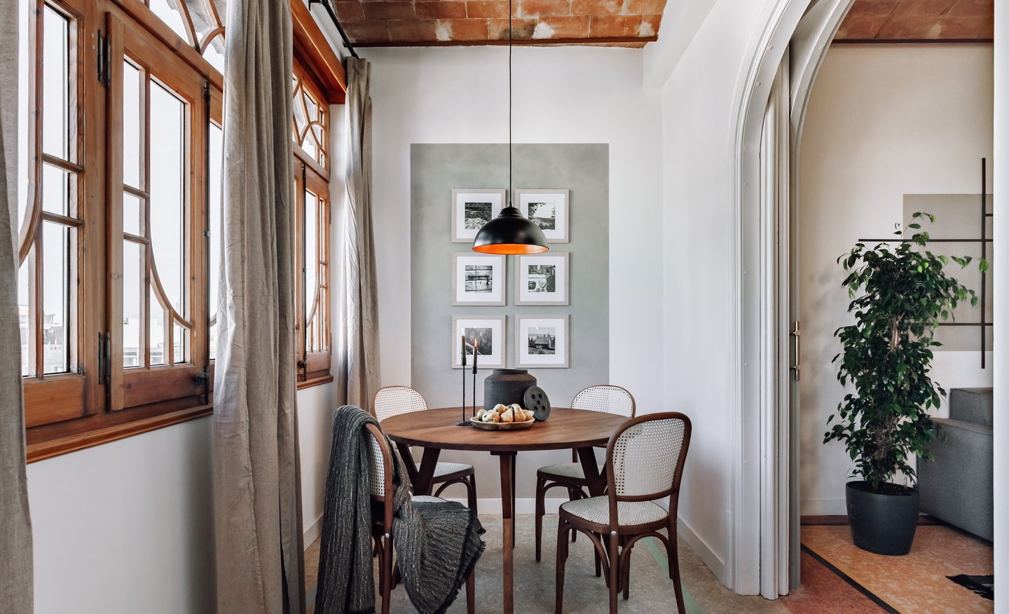 Elegant dining area with rattan and wood chairs and rustic decor elements by SAVIA interior design