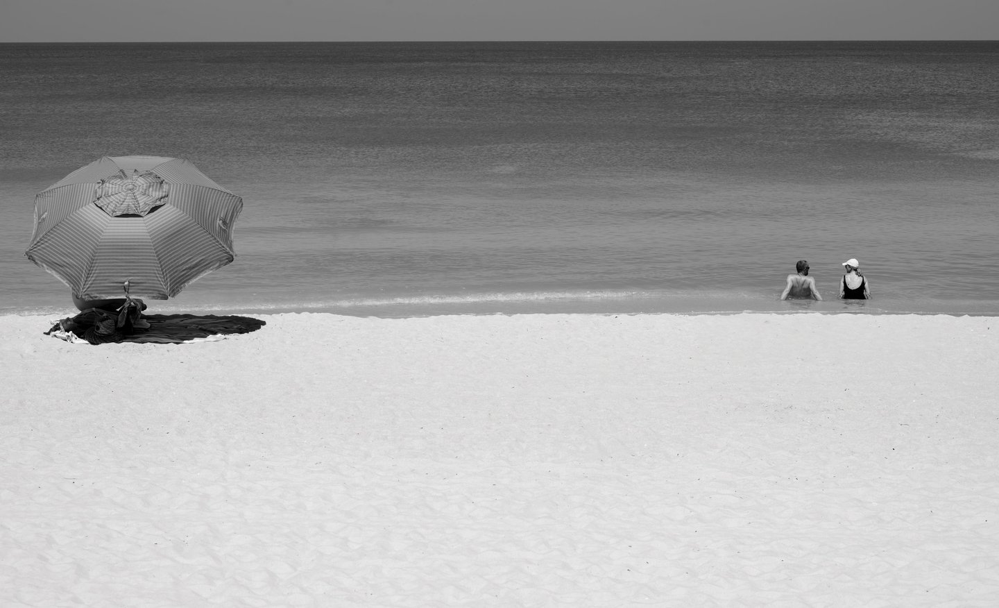 beachgoers in the gulf of mexico and under a beach umbrella and sand in naples florida