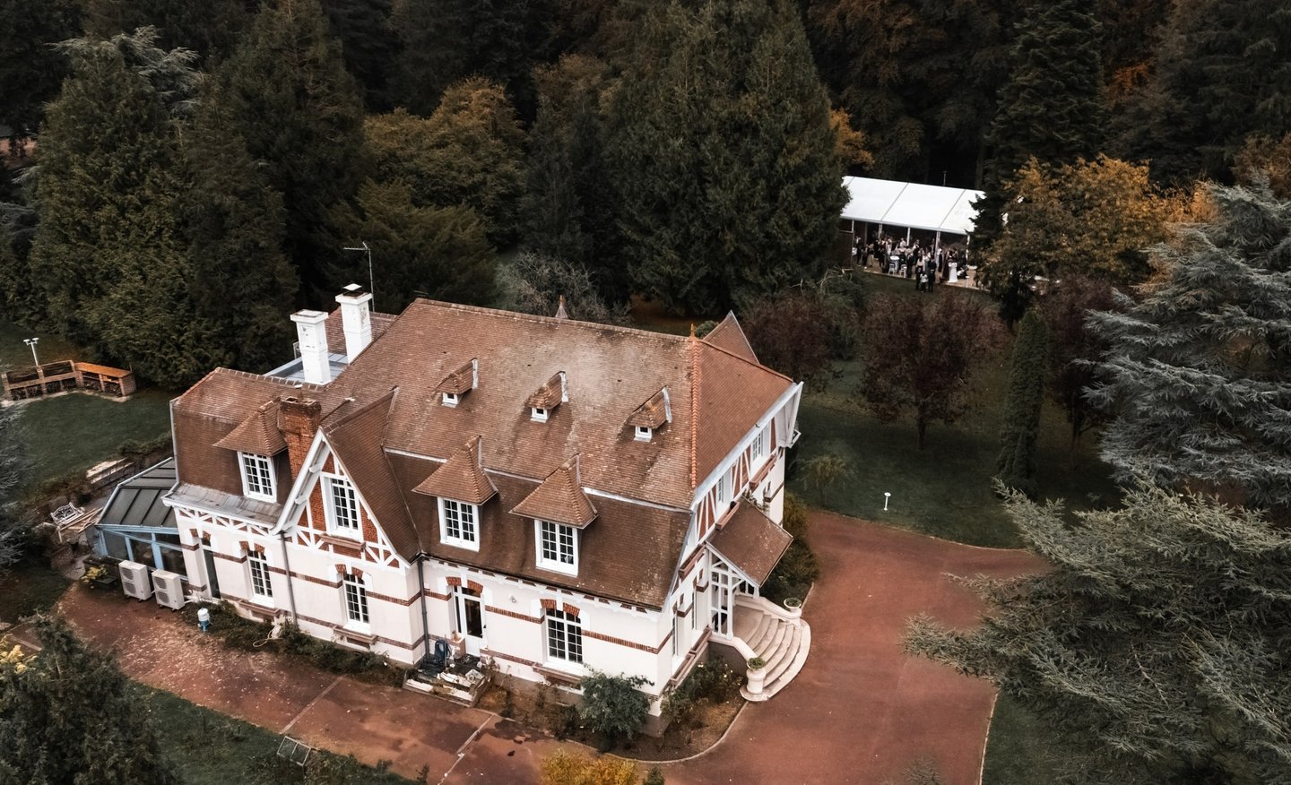 Une maison normande vue du ciel dans un parc boisé