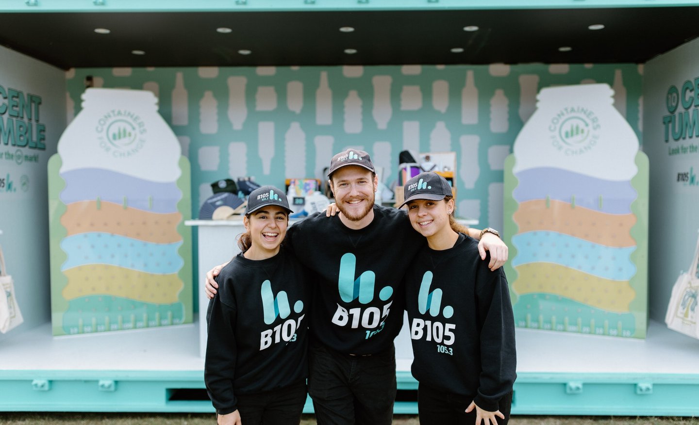 three people standing in front of a large containers for change stand