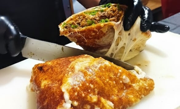 a person cutting a sandwich with a knife and knife