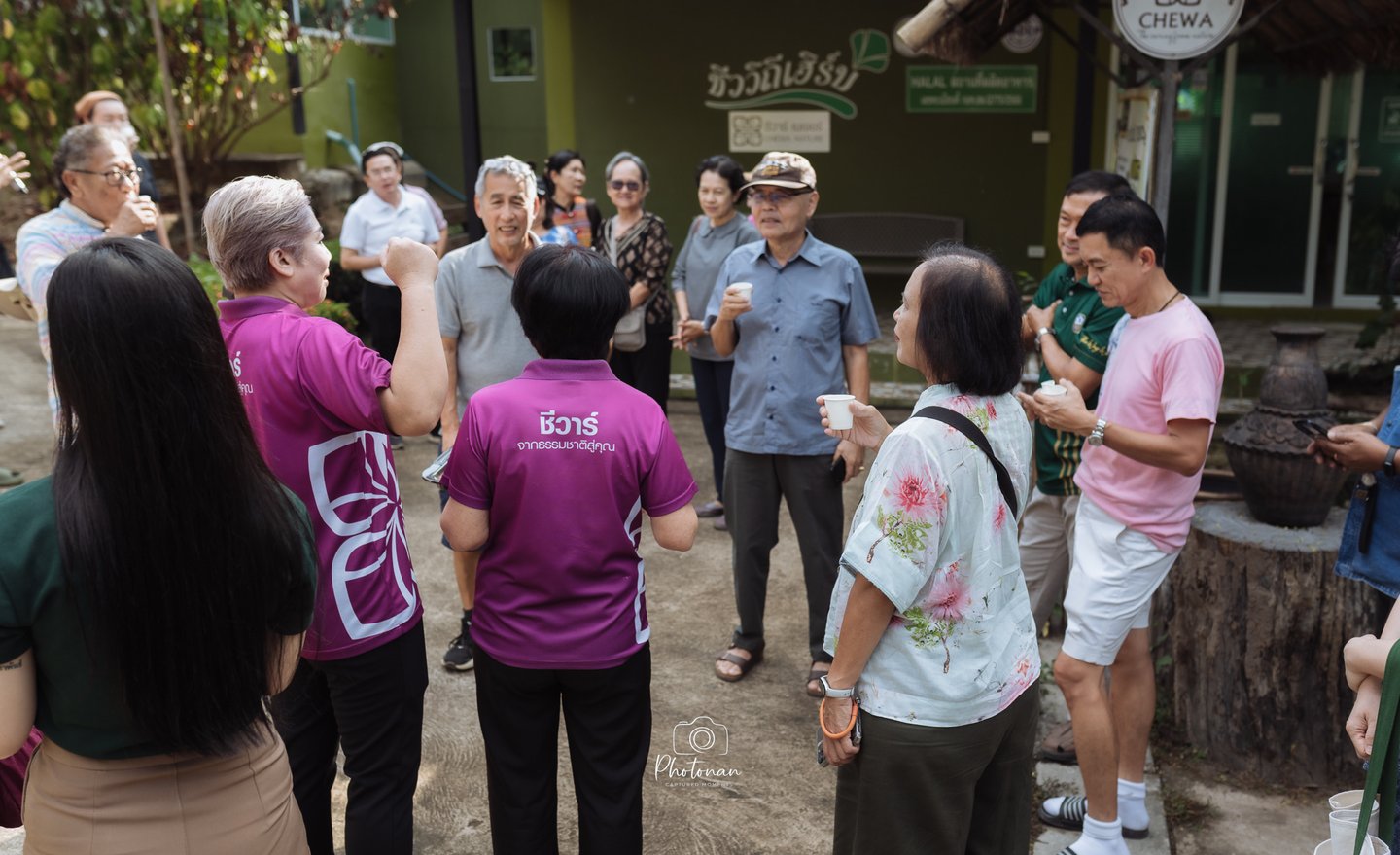 ภาพถ่ายหมู่คณะหน้าศูนย์วิสาหกิจชุมชนบ้านน้ำเกี๋ยน จังหวัดน่าน พร้อมป้ายยินดีต้อนรับและสินค้า OTOP