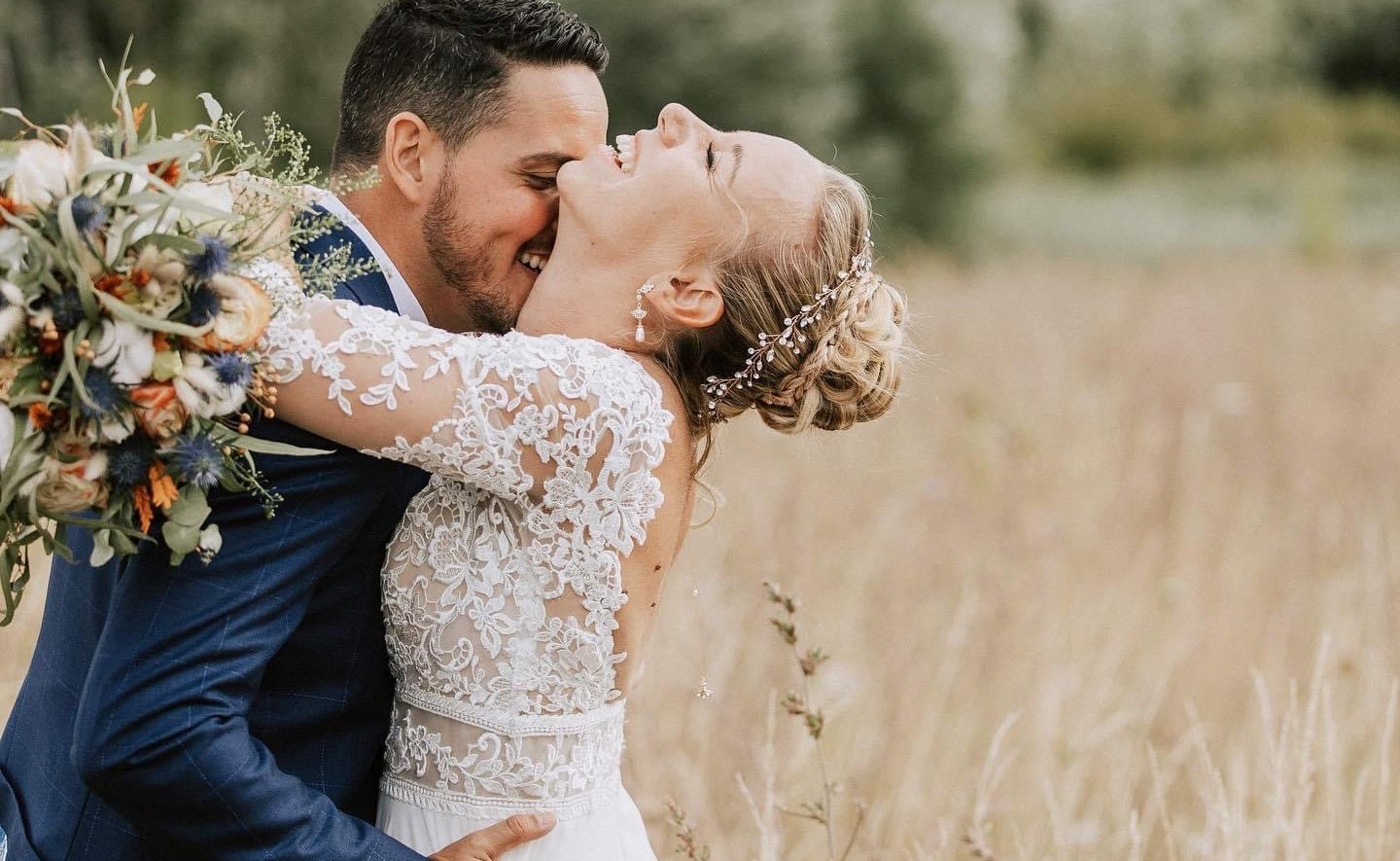 une mariée et un marié s'embrassant dans un champ