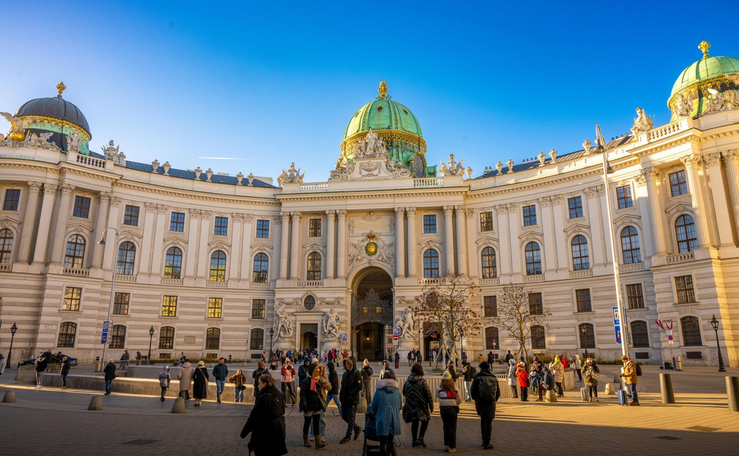 Tourists walk in front of the Hofburg Palace at Michaelerplatz in Vienna, Austria.