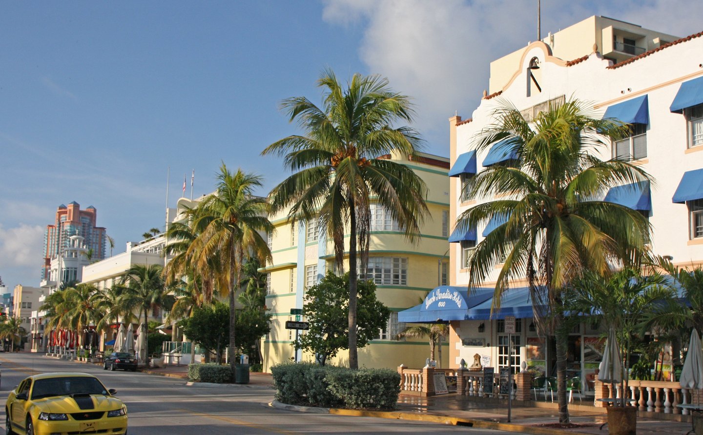 Pastel-colored Art Deco hotel facade in Miami Beach's historic district with palm trees"