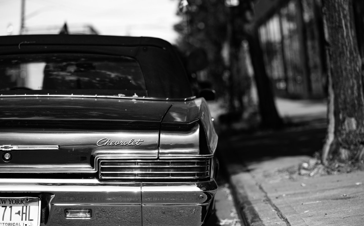 a classic chevrolet car with a soft top and ny license plates parked on a brooklyn street