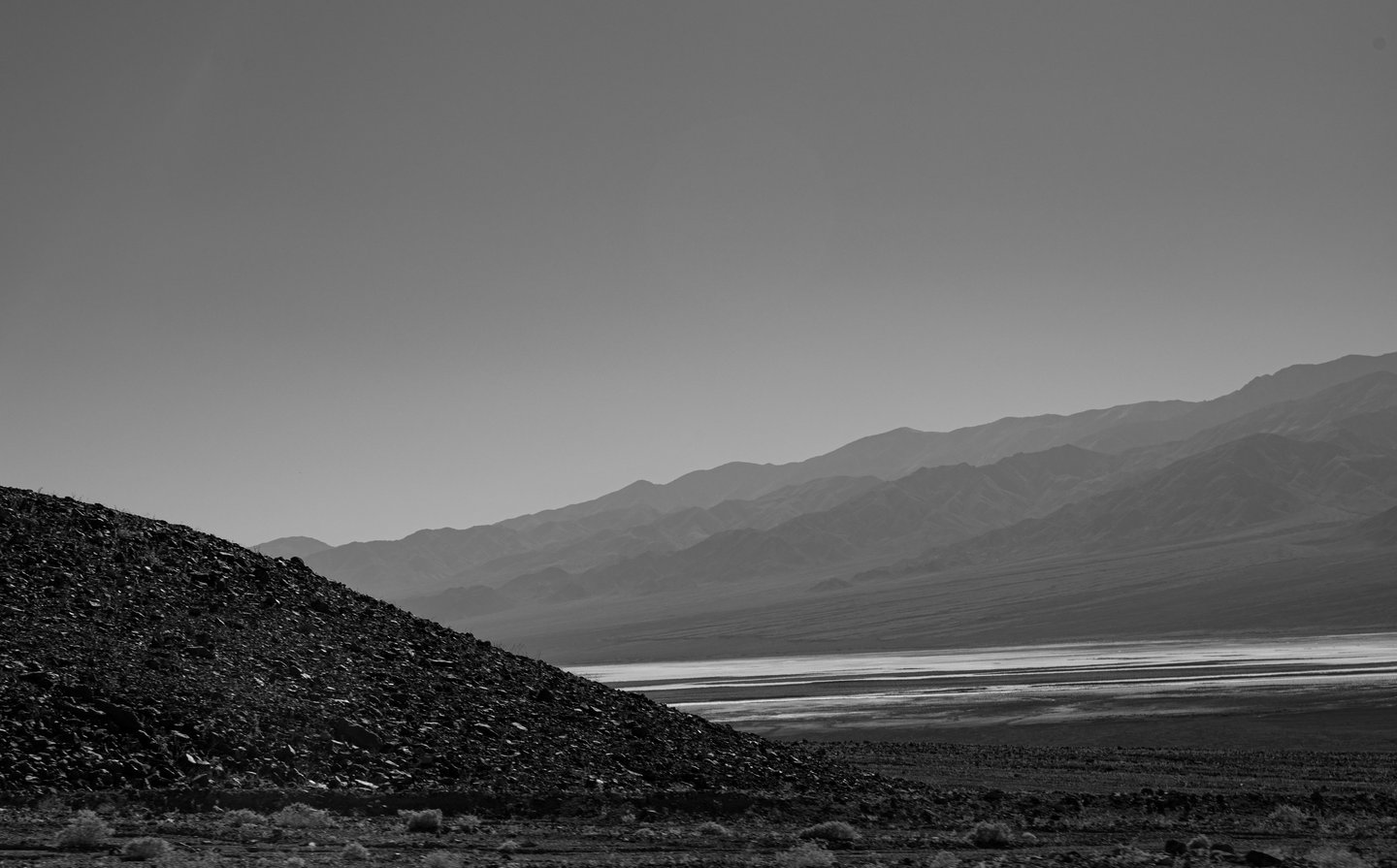 a spooky hazy black and white mountain range and salt basin in death valley