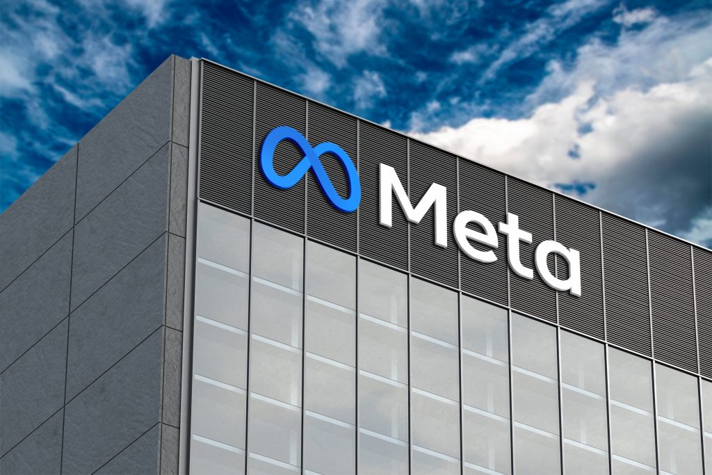 Low-angle view of the blue infinity symbol and Meta logo on a modern glass office building exterior.