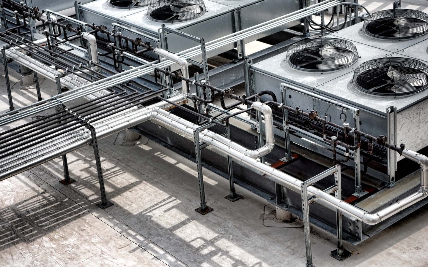 Industrial rooftop refrigeration gas coolers system with large fans and complex steel piping.