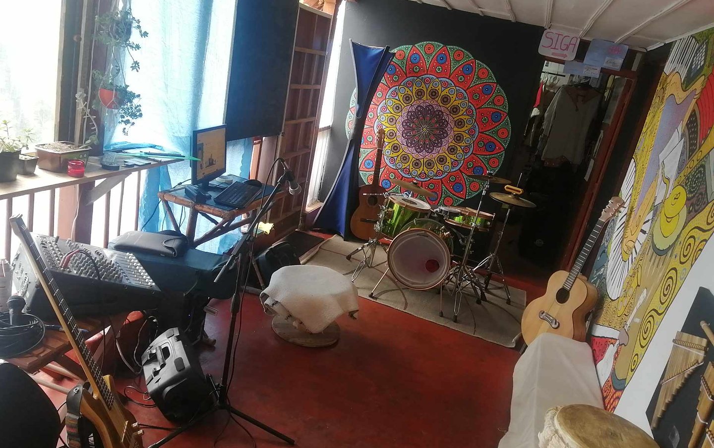 Sala con instrumentos musicales, en una de las paredes un mandala pintado, espacio con plantas