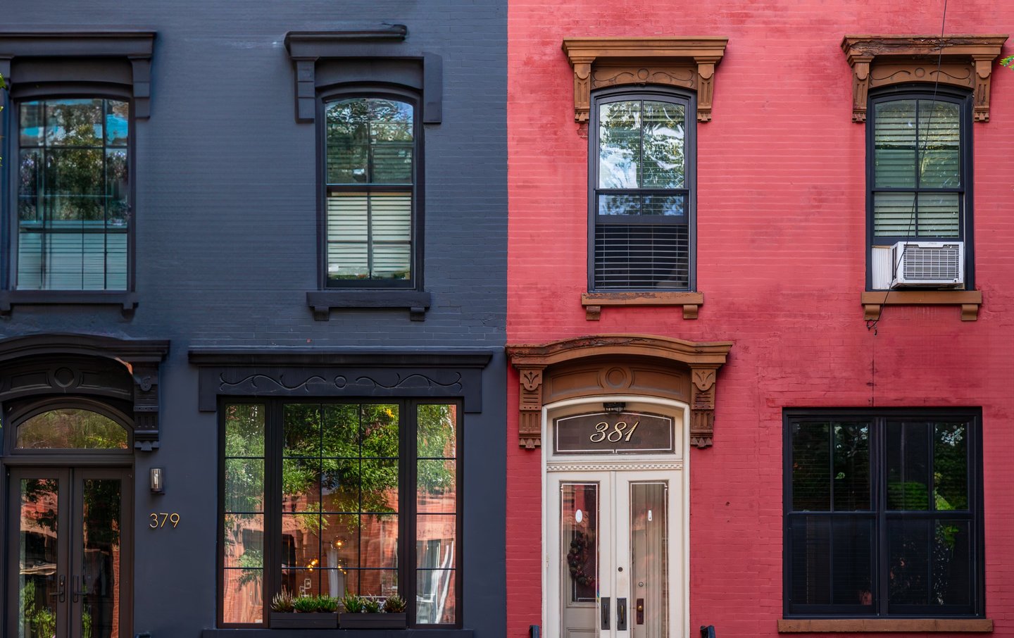 a symmetrical pair of red and gray brownstone buildings and doors and windows in brooklyn ny