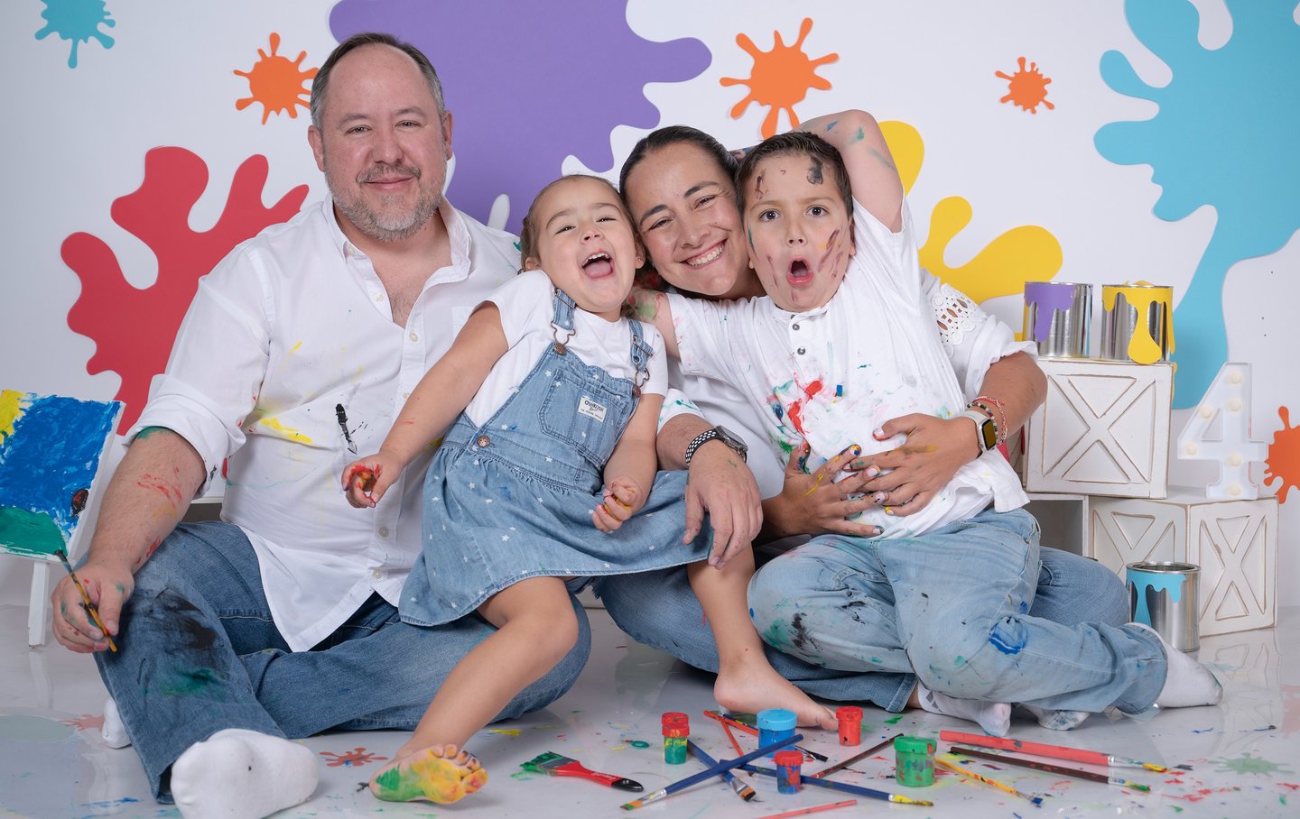 a family posing for a photo in front of a wall with paint splatters