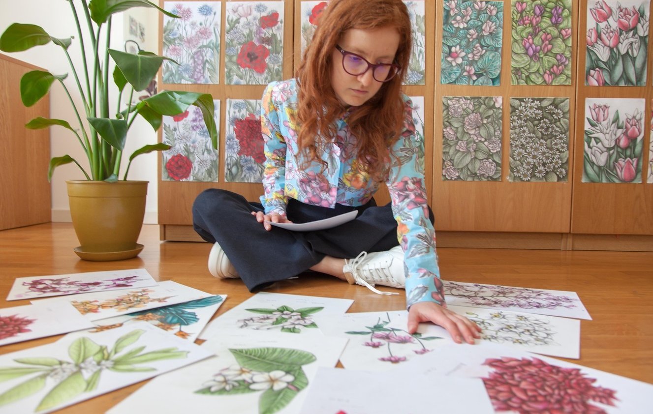 A Woman sat on the floor surrounded by botanical illustrations