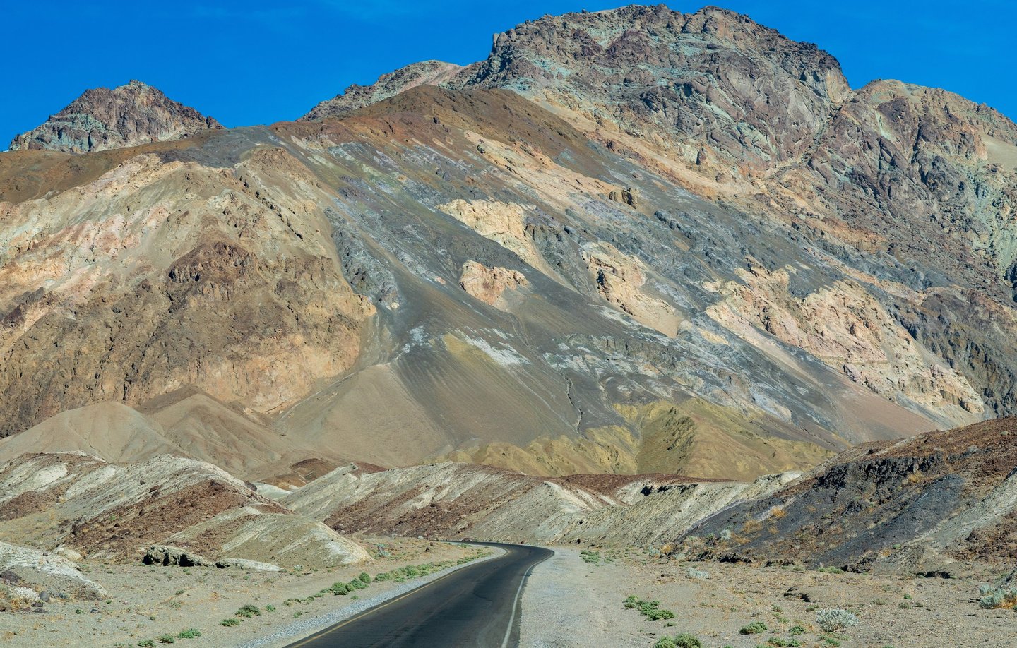 a road fading into the colorful facades of artists palette in death valley national park