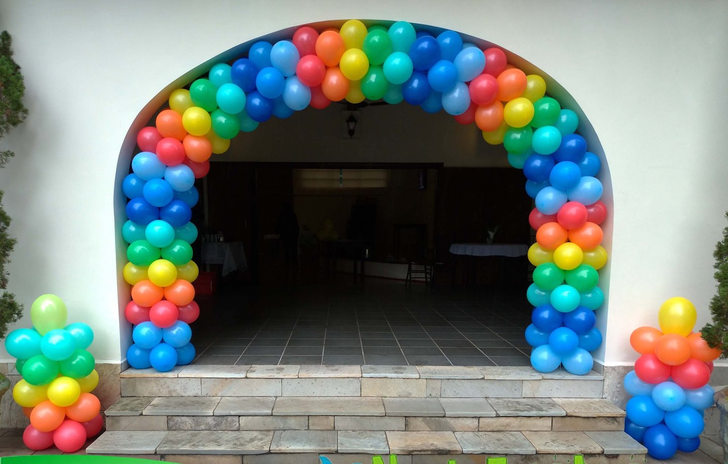 Arco de balões colorido na entrada de aniversário, criando ambiente alegre e acolhedor.