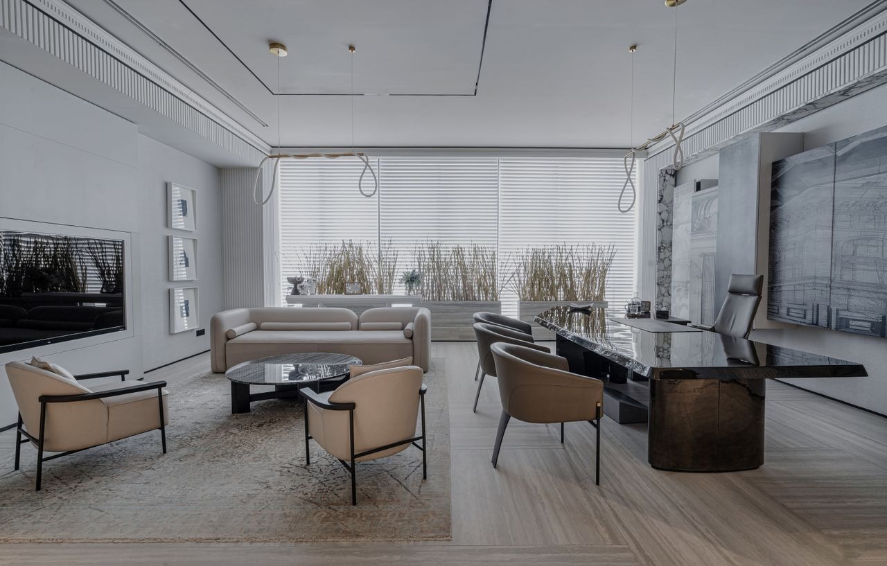 Modern luxury executive office interior with a black marble desk, cream lounge chairs, and minimalist decor.