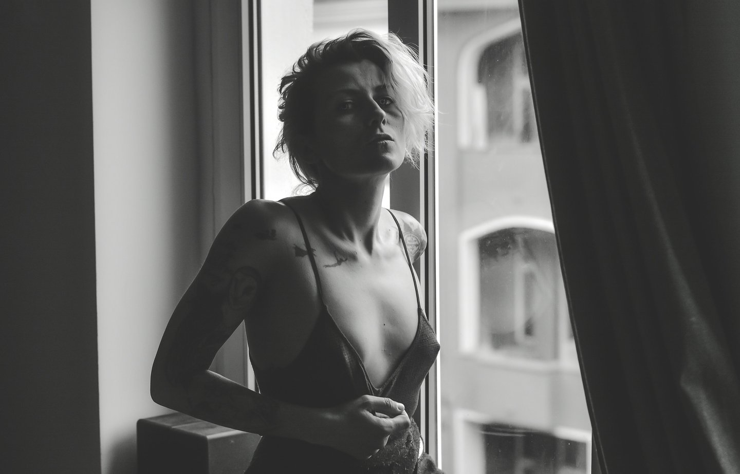a woman in a lingersuit sitting on a window sill posing for a photo