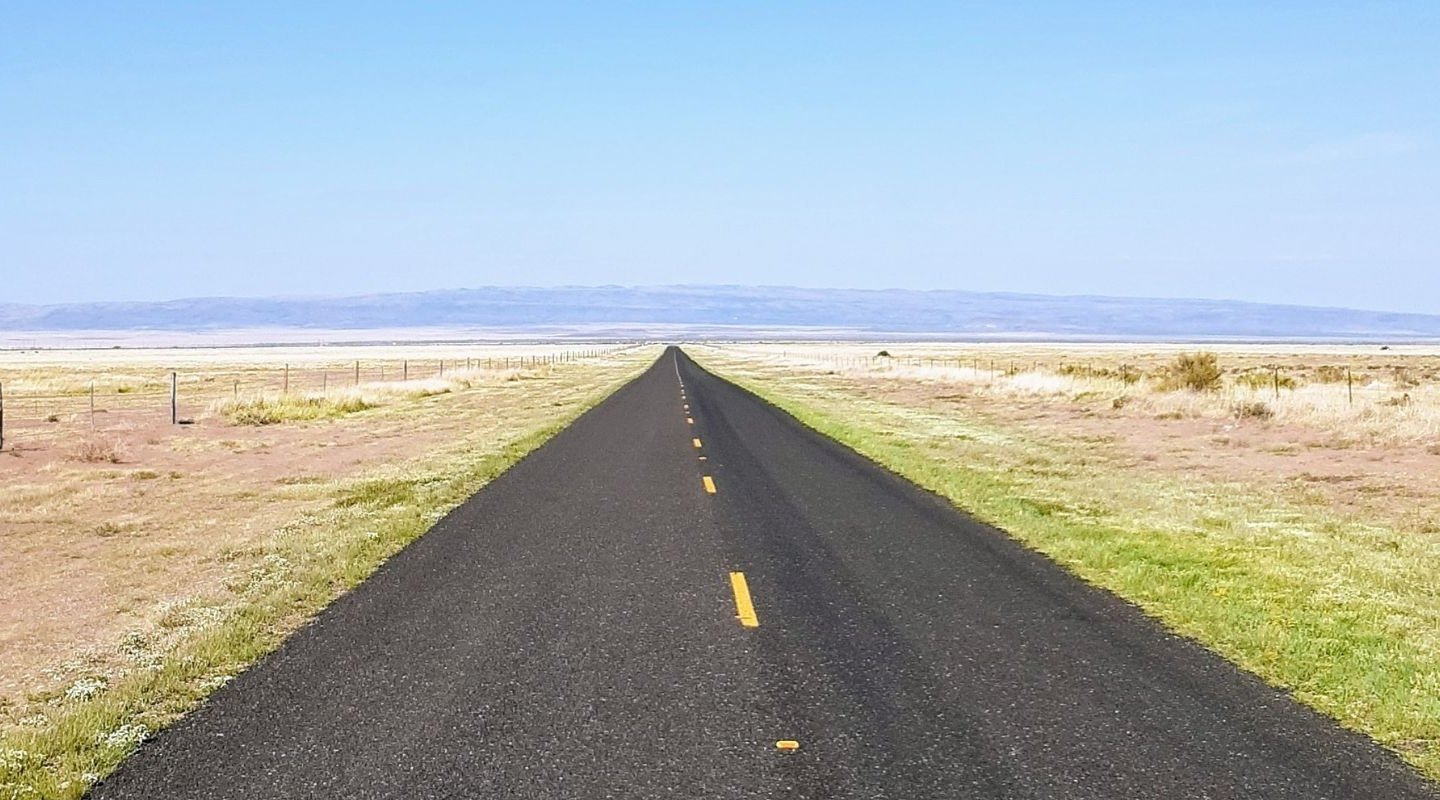 Isolated two-lane road converging at mountains in distance