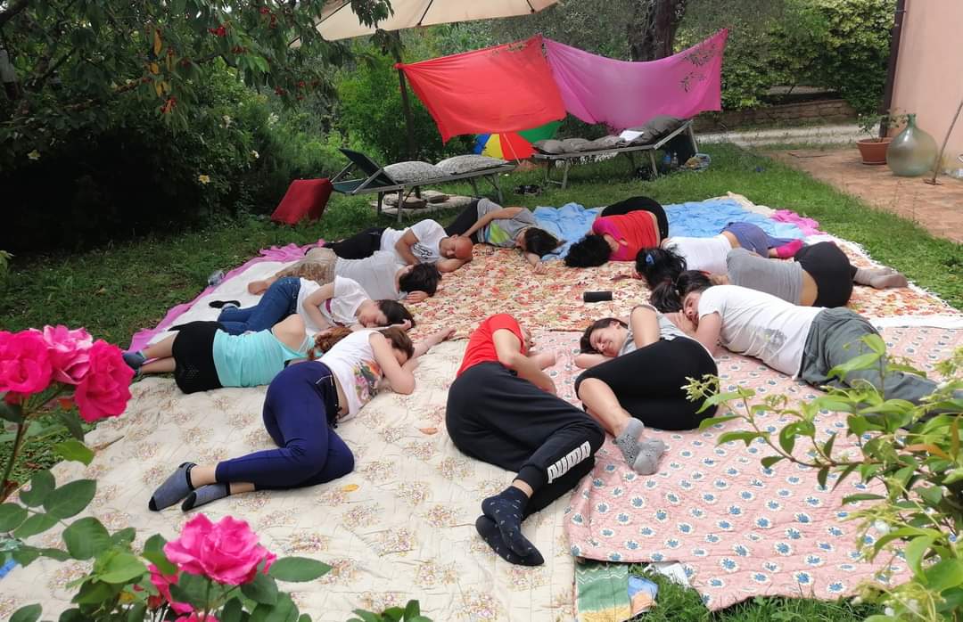 a group of people sitting on a blanket on a blanket, rilassamento, classe bioenergetica