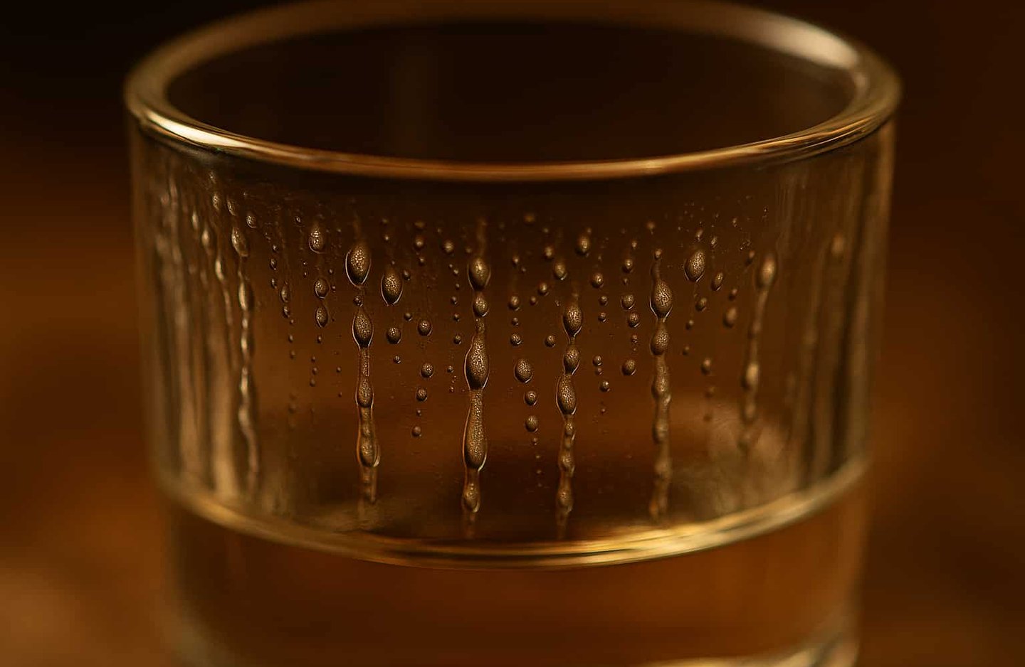 Close-up de perlas deslizándose en vaso de mezcal artesanal