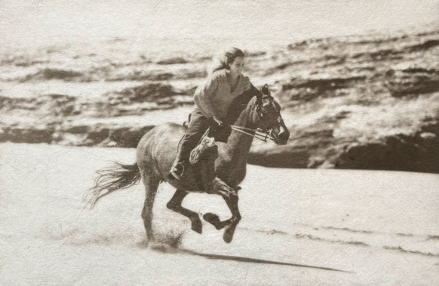 Black and white photograph in silver and Platinum of a woman riding a horse on a beach