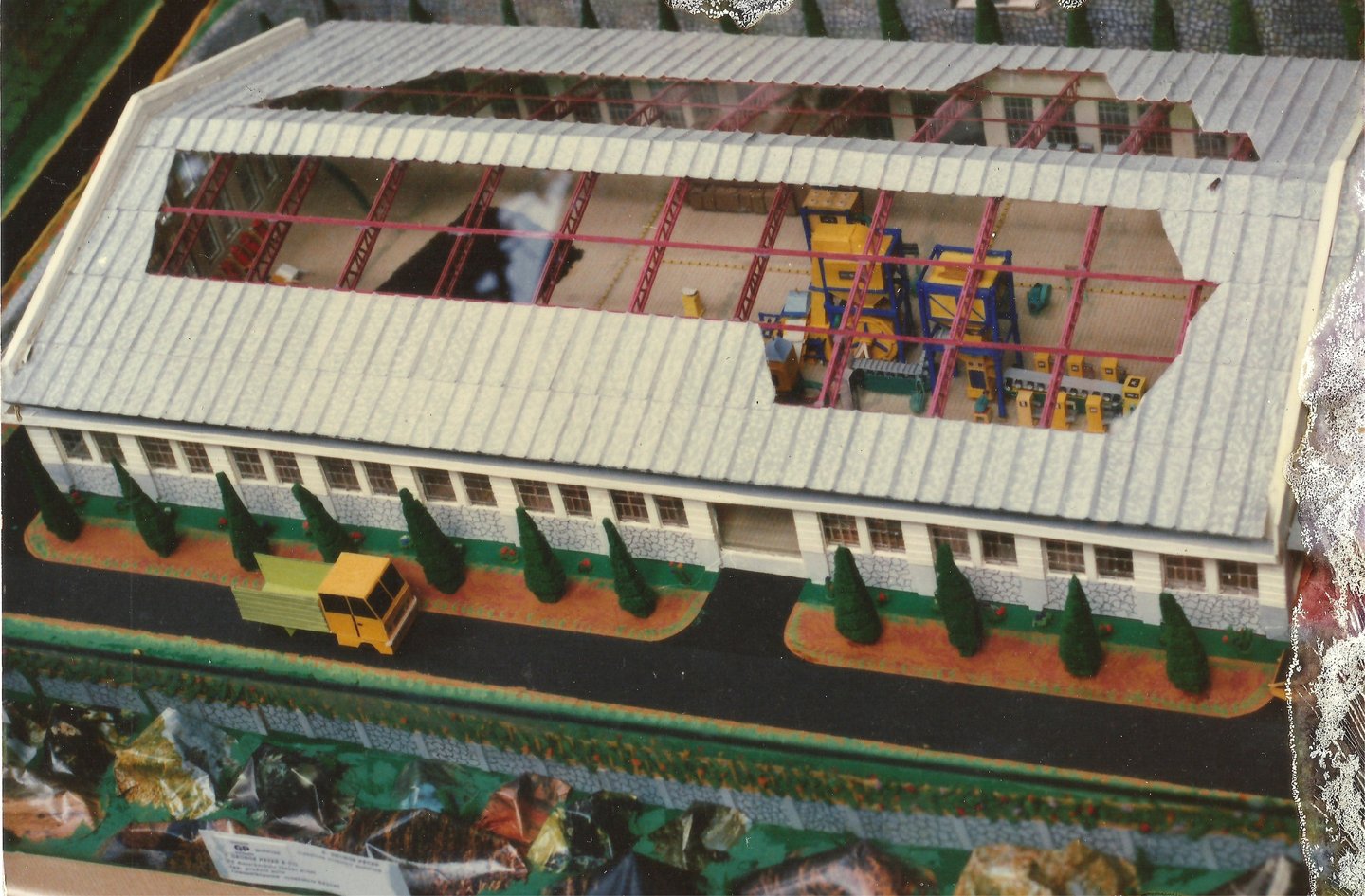Scale model of an industrial warehouse facility featuring a cutaway roof and interior machinery 1975