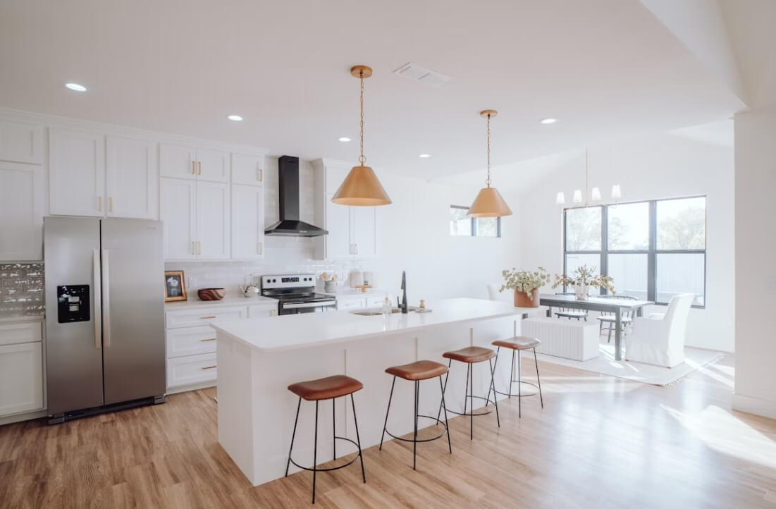 Kitchen remodel with a large island, bar seating, pendant lighting, and stainless steel appliances.