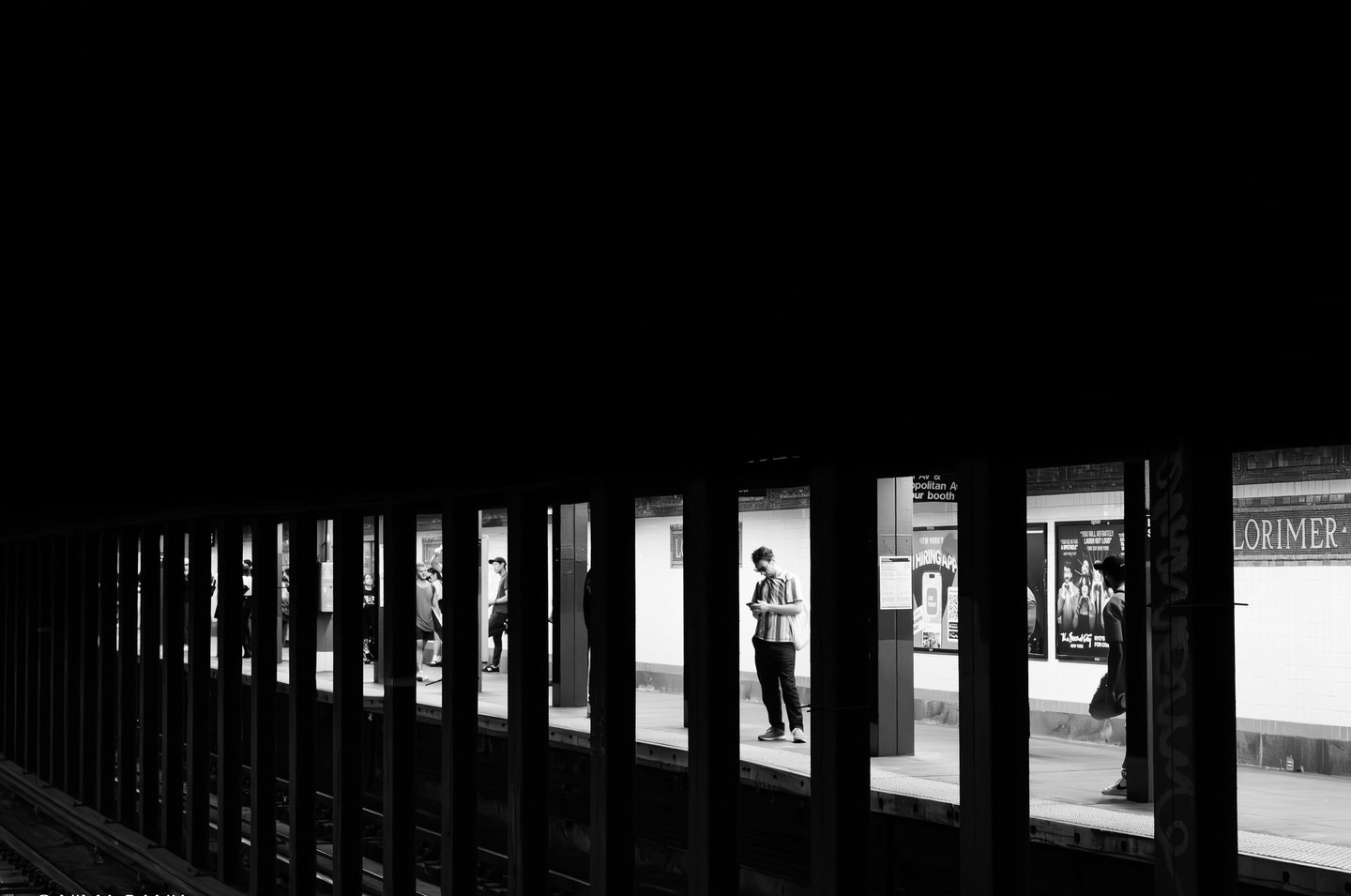 black and white photo depicting shadows of a subway station against the contrast of riders waiting