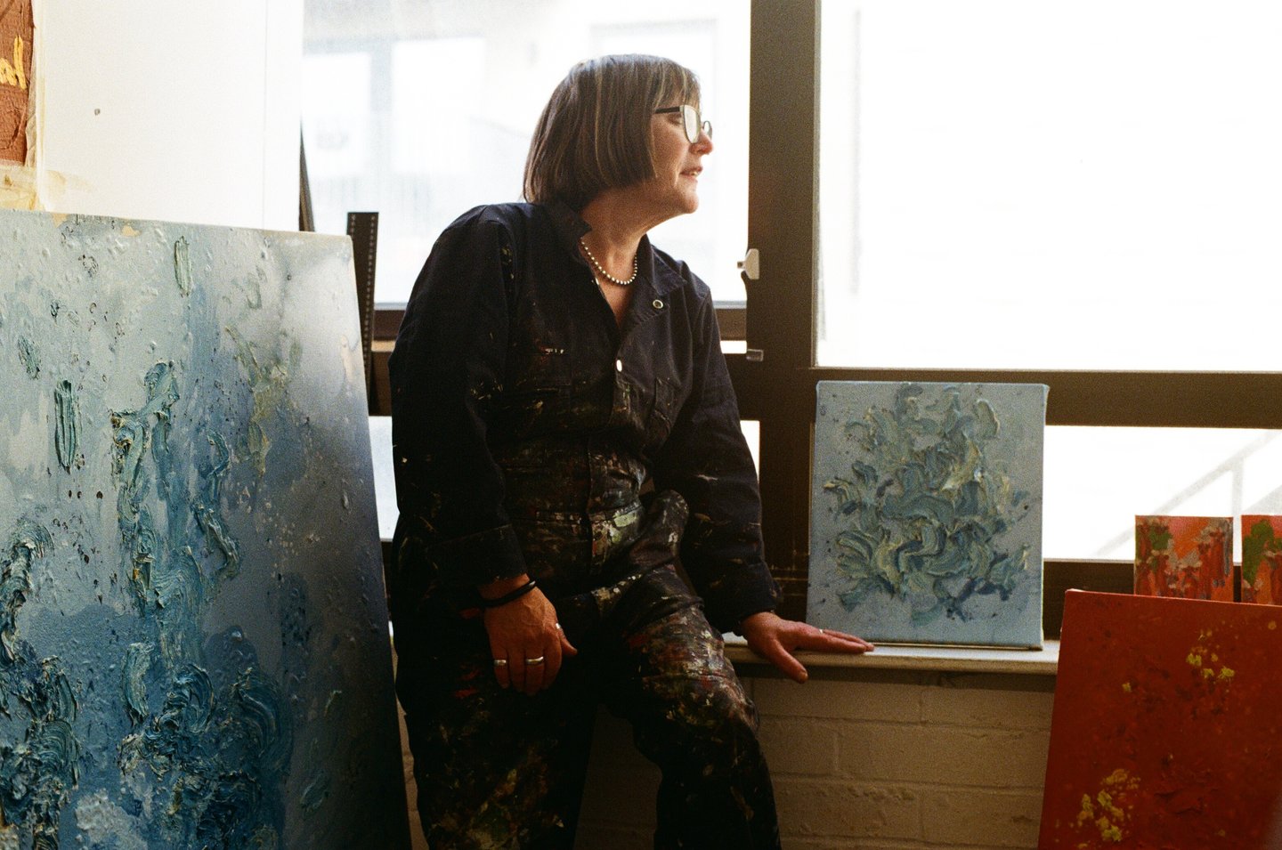 a woman sitting on a window sill with a laptop computer