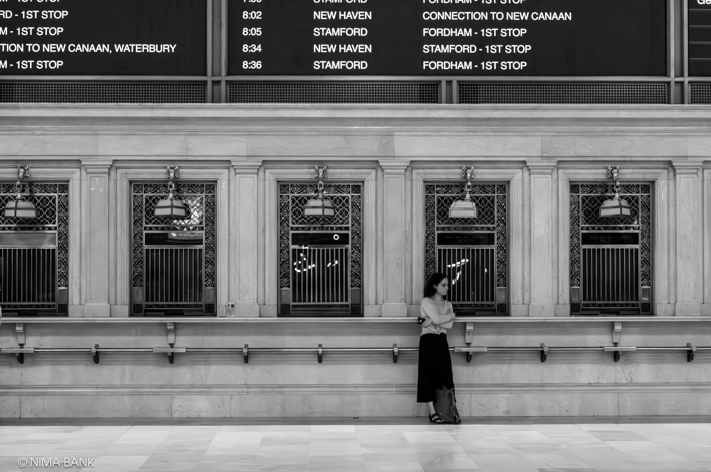 a woman standing in front of a wall with a clock at the grand central terminal main lobby