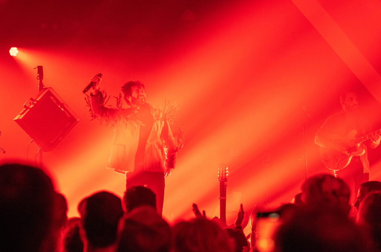 a man in a white shirt and a microphone in front of a red light