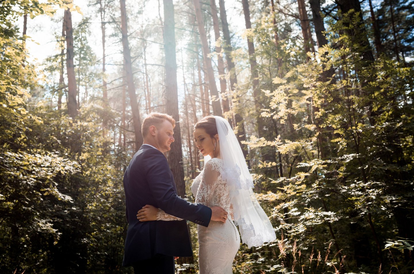 a bride and groom standing in a forest