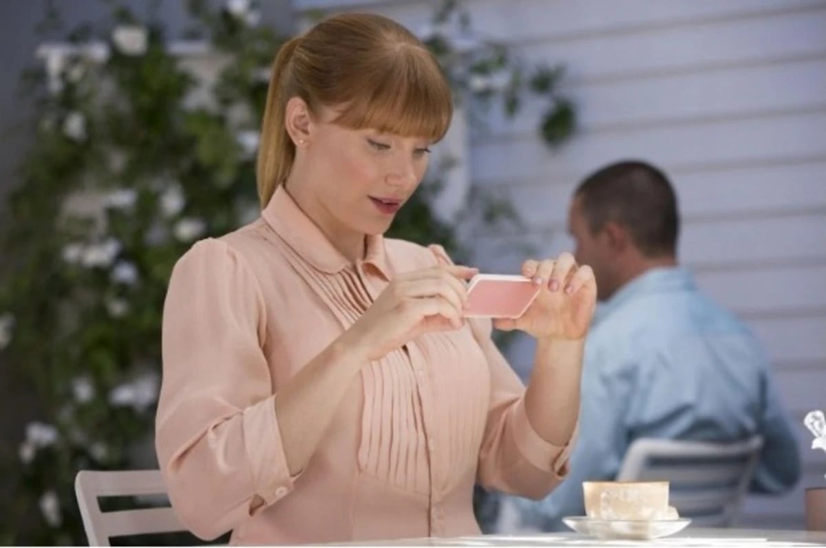 a woman in a pink shirt is holding a cell phone