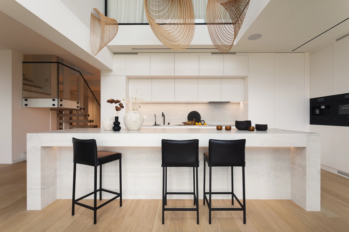 Nowoczesna biała kuchnia z dużą wyspą i ażurowymi lampami.