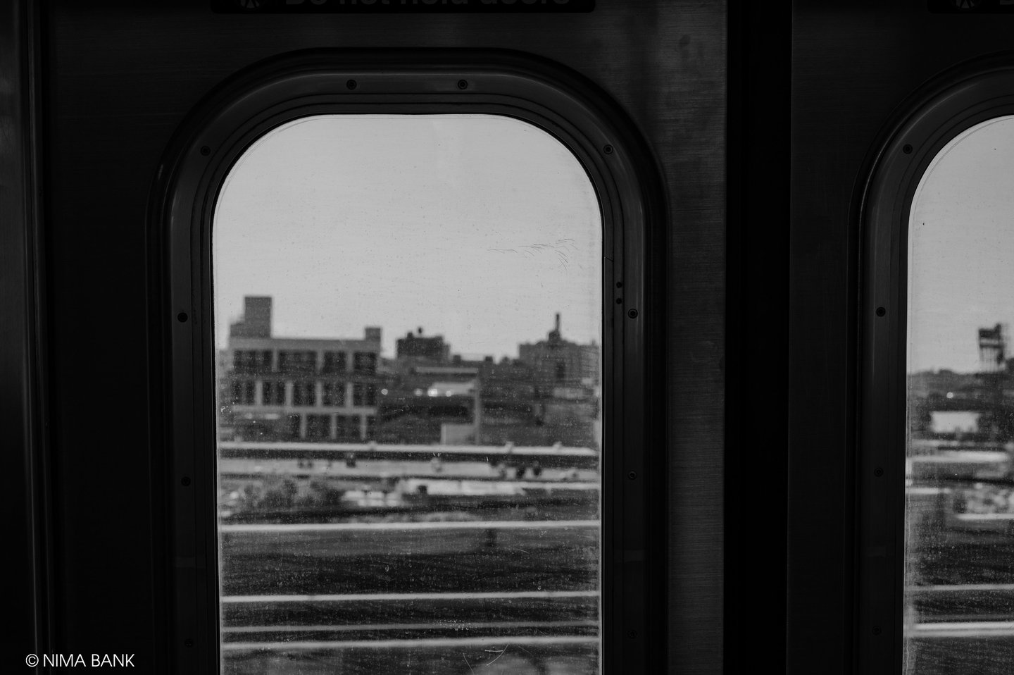 black and white scene of the inside of a brooklyn subway car with a blurred view outside the car