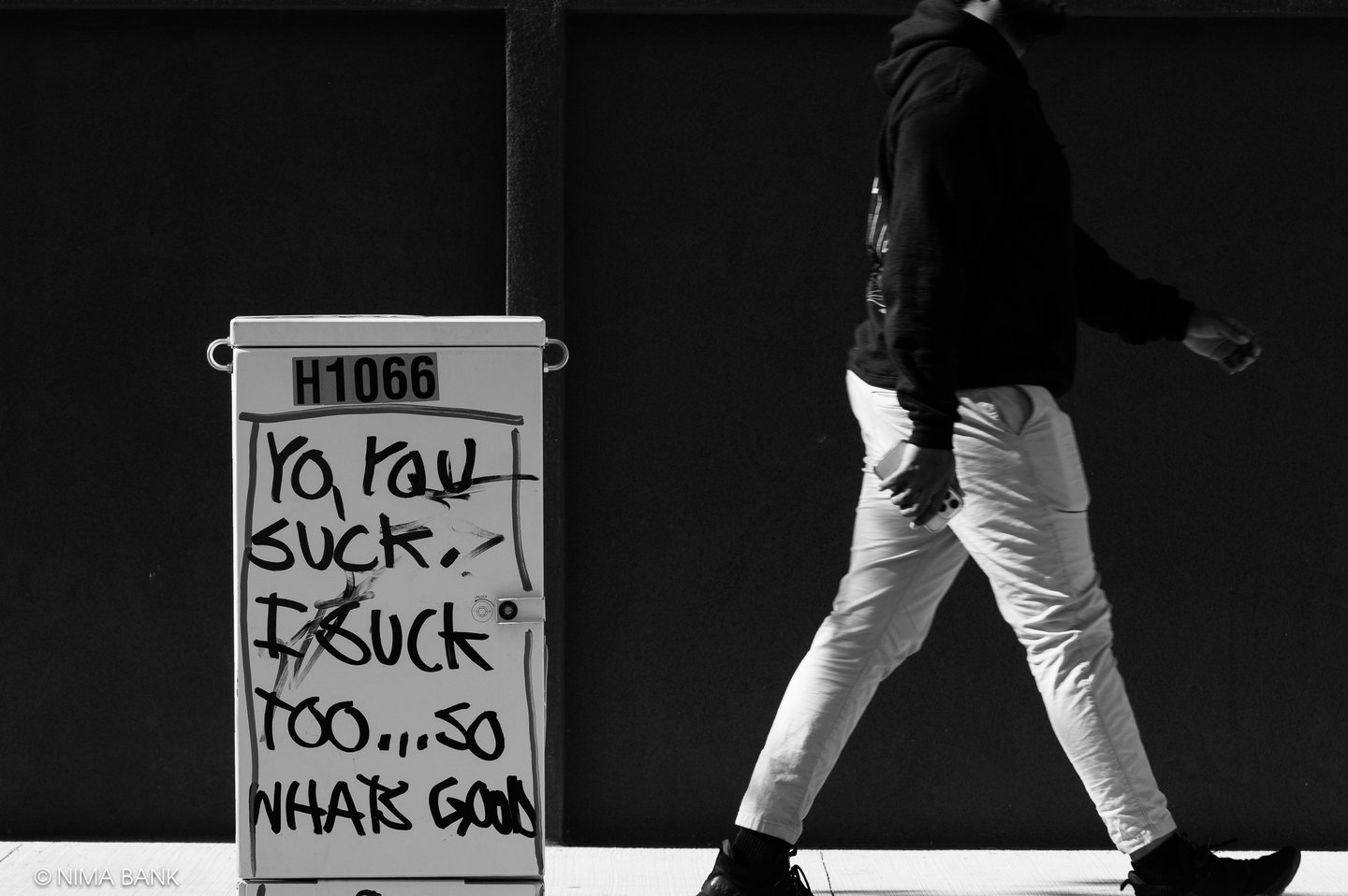 street image of a sign sitting on the sidewalk in brooklyn with a man walking through the frame