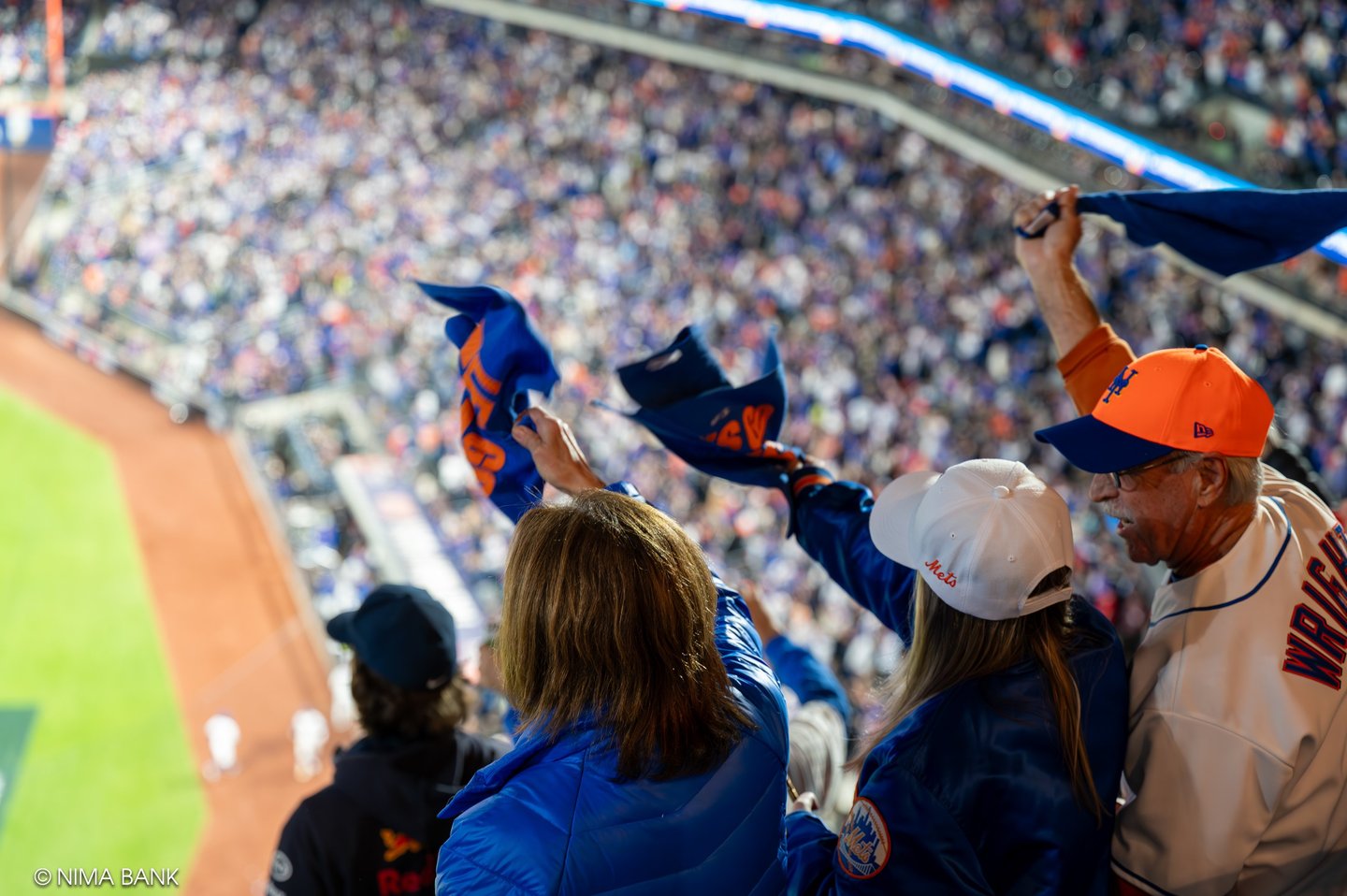 mets fans wearing team gear waving playoff rally towels in citifield overlooking the stadium 