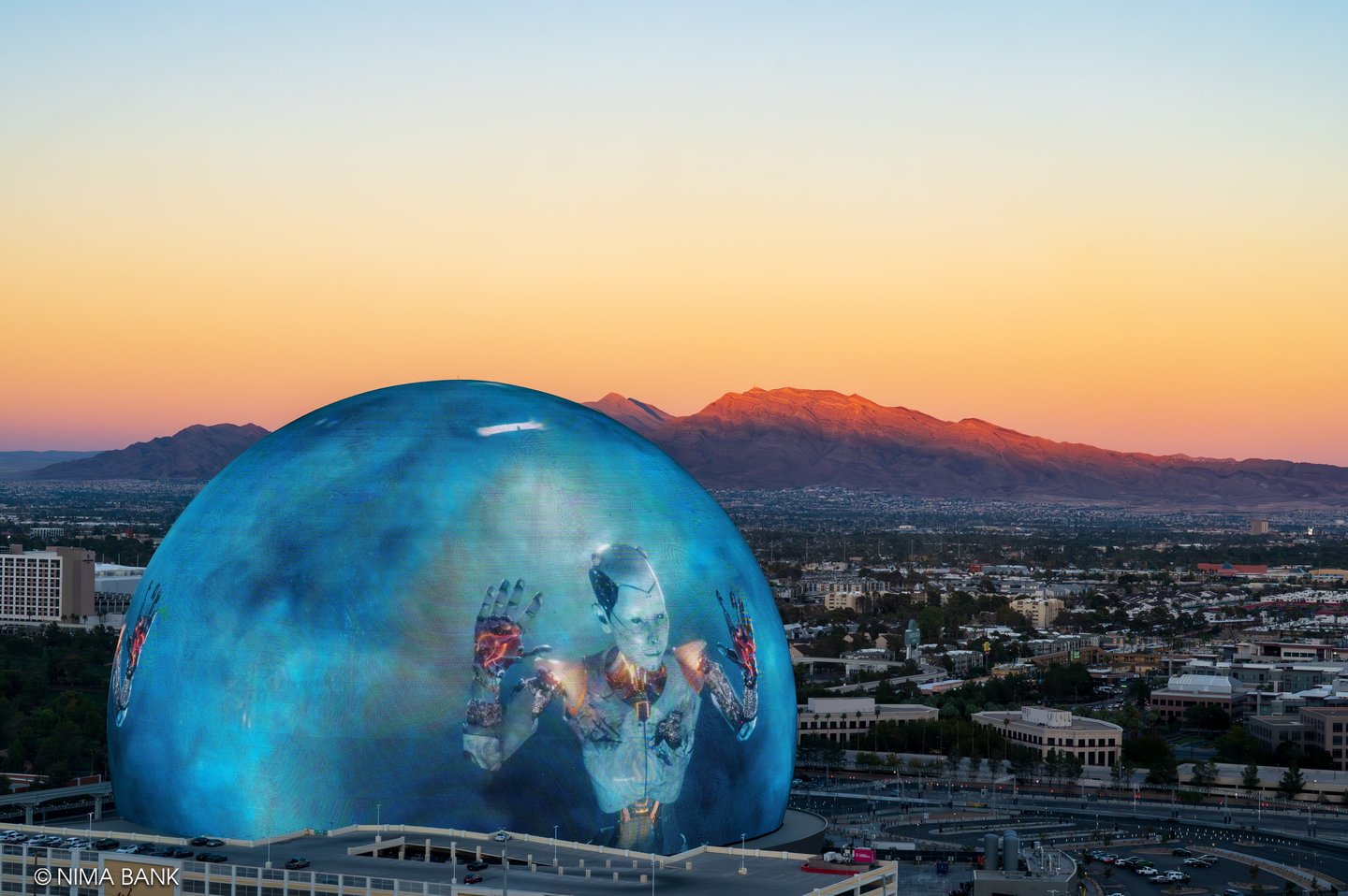 image of a cyborg on the sphere in las vegas, taken from atop the high roller, with mountains 