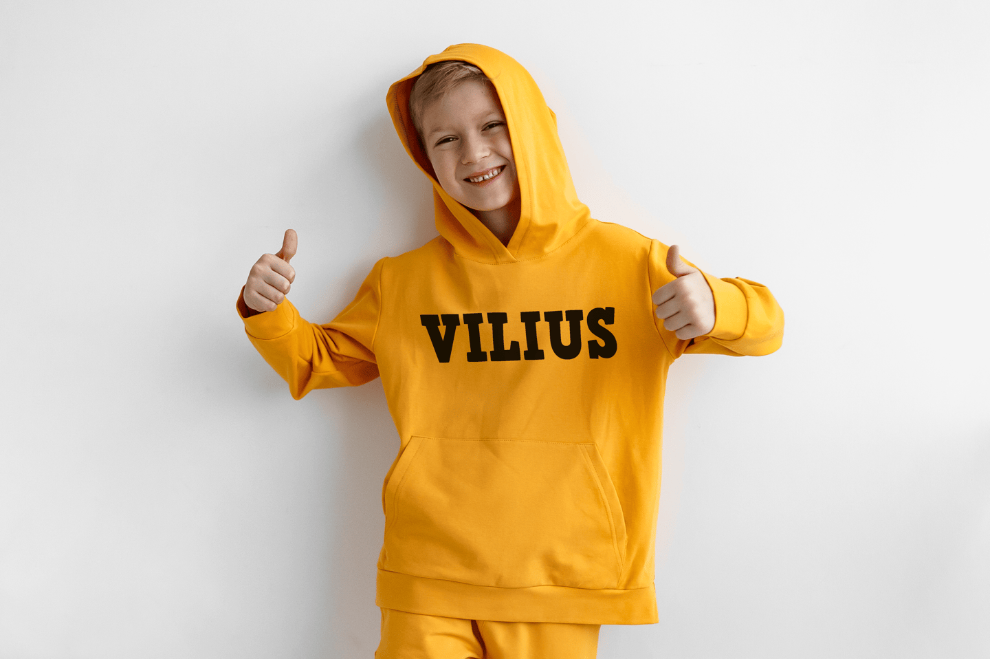 vaikas su geltonu dzemperiu ant kurio yra parasytas vardas Vilius