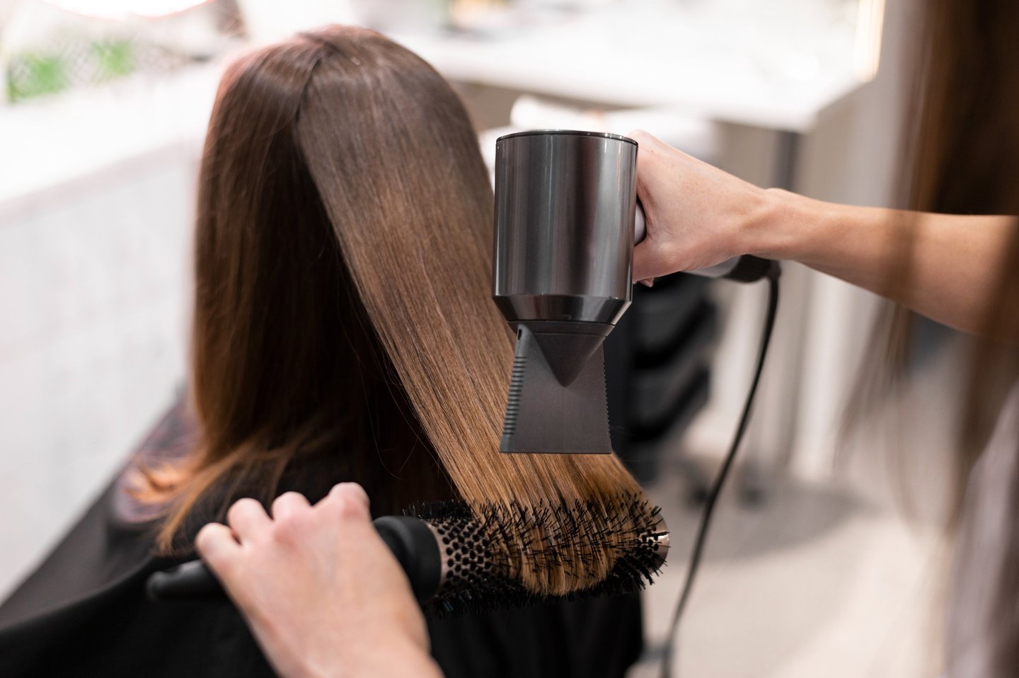 a woman is blow drying her hair in a salon